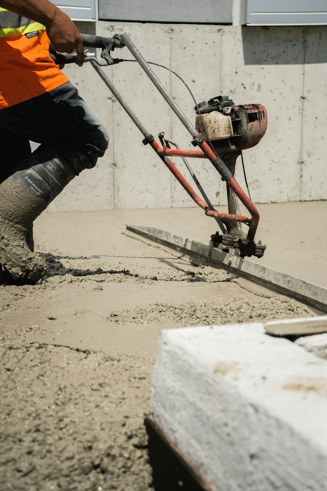 Concrete worker using screed machine