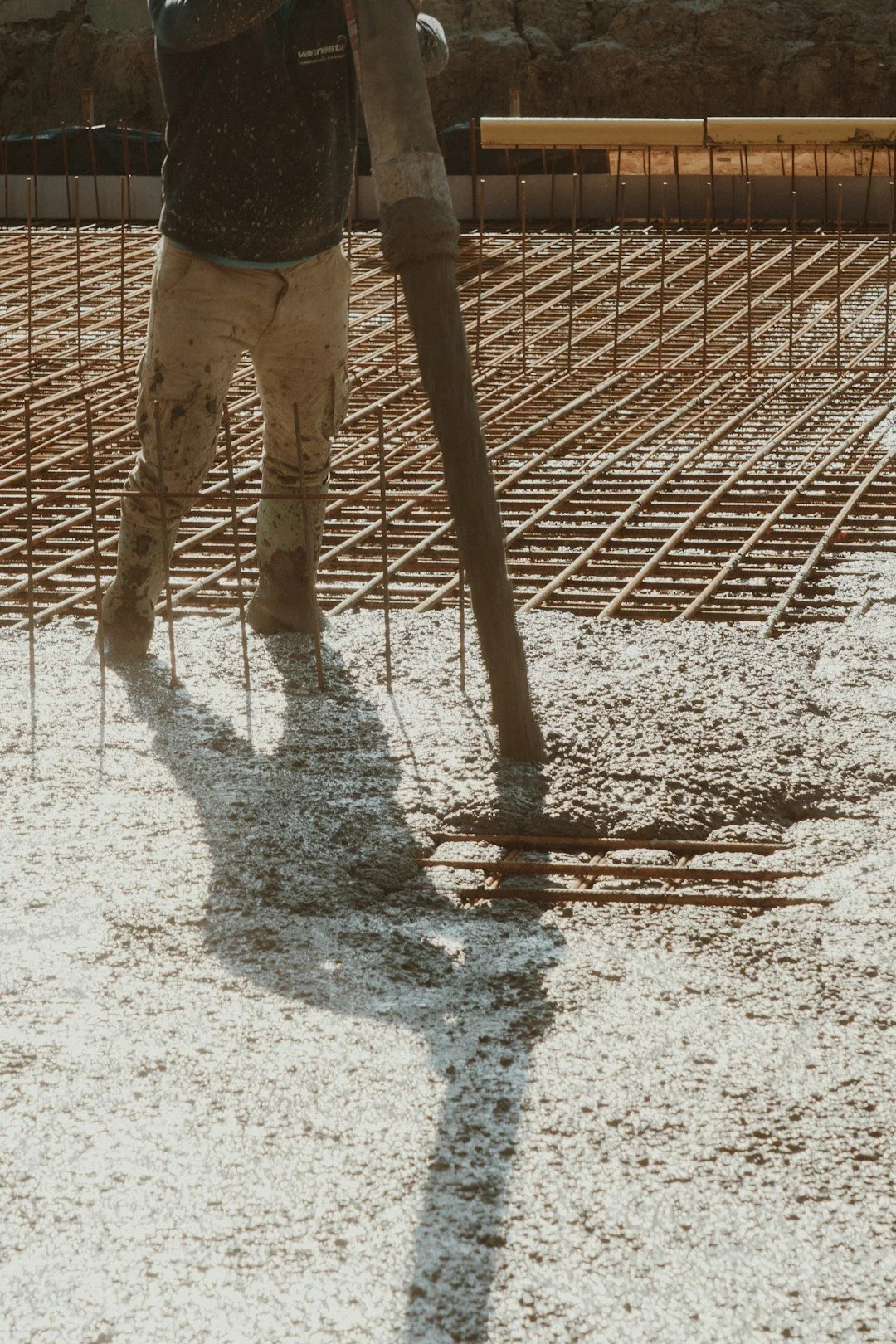 Worker pouring concrete over rebar